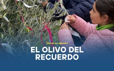 Una fotografía del Olivo del Recuerdo con las cintas de colores colgadas por los alumnos, o bien una imagen simbólica con niños alrededor del árbol, con luz natural y ambiente de recogimiento.